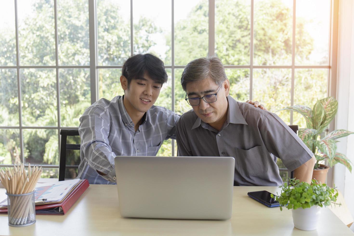An elderly Asian man is learning how to trade online through the Internet with his instructor son. photo