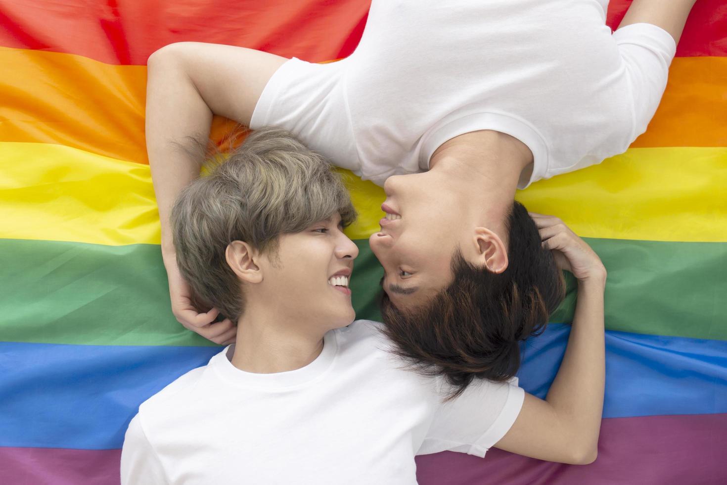 parejas masculinas con hombres asiáticos duermen en una bandera multicolor con un logo lgbt que muestra a hombres abiertamente homosexuales que aceptan conceptos lgbt. foto