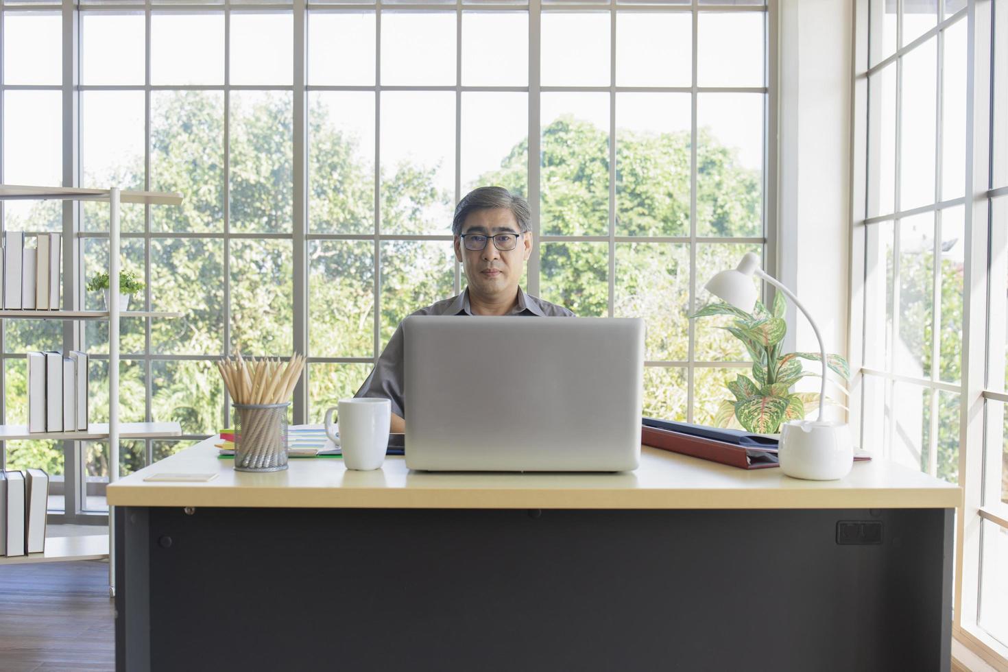 Asian middle-aged man sitting at a desk in an office. photo