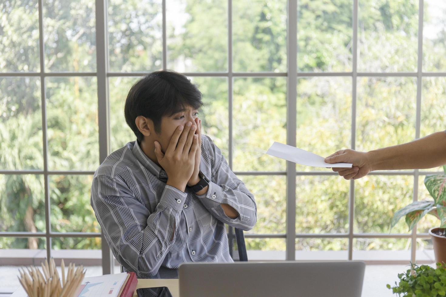 Hand delivering documents to a sad young Asian man with bad news Desperate entrepreneurs get laid off Frustrated by business bankruptcy or fired. photo