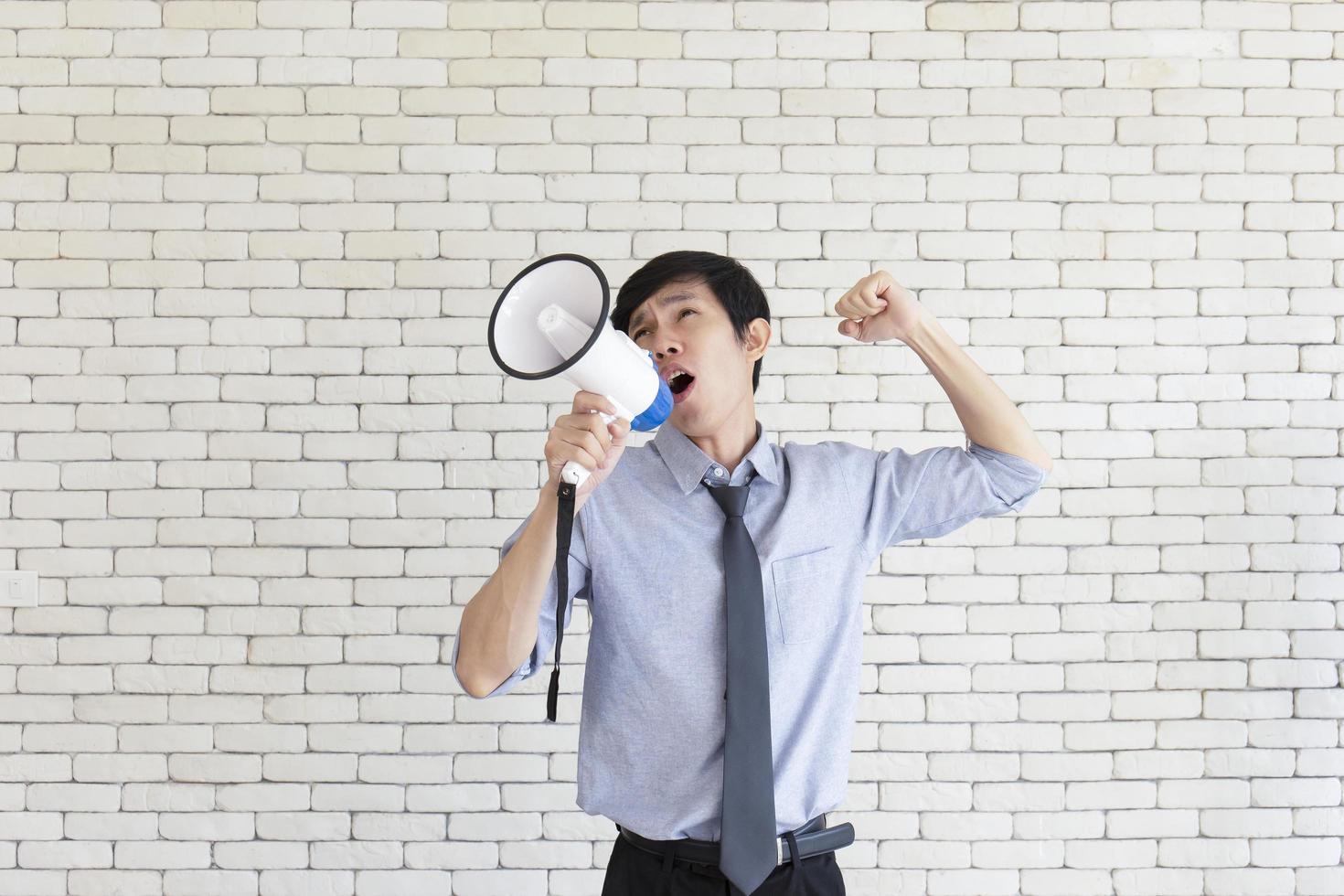 A young Asian man grabbed a megaphone and shouted with an angry expression. photo