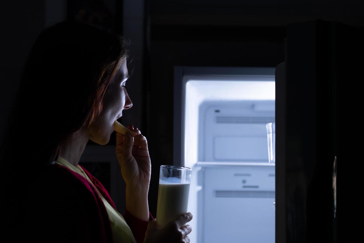 A pregnant woman who wakes up late at night looking for food in the refrigerator photo