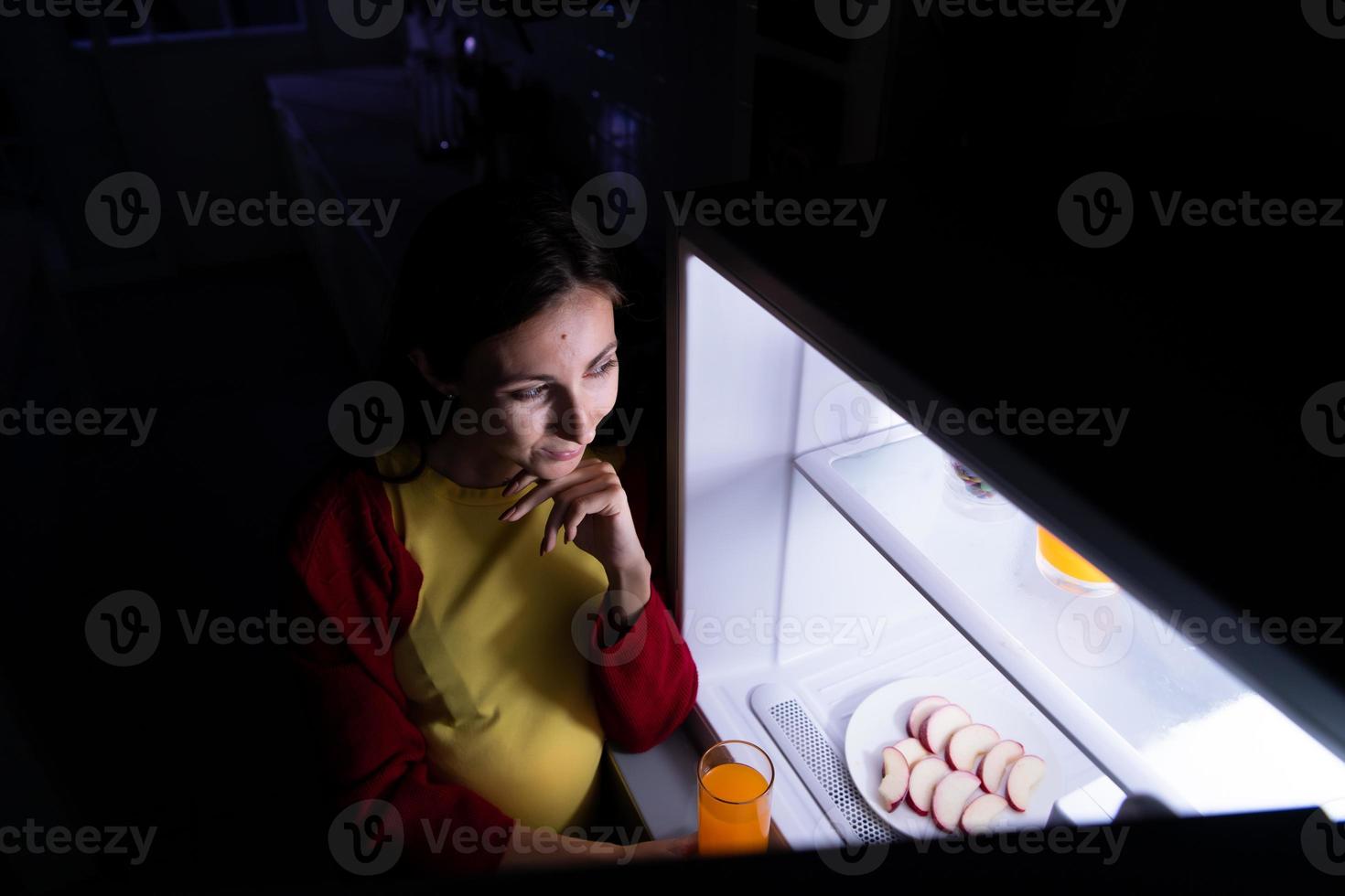 A pregnant woman who wakes up late at night looking for food in the refrigerator photo