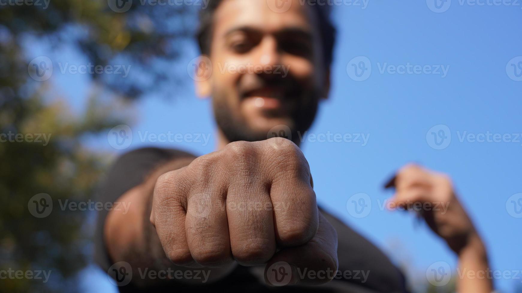 joven apuesto indio mostrando nuestro golpe a la cámara foto