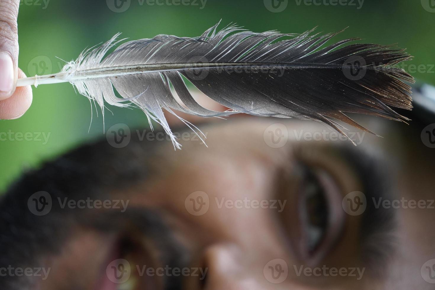 close up face a boy withe feather playing with feather photo