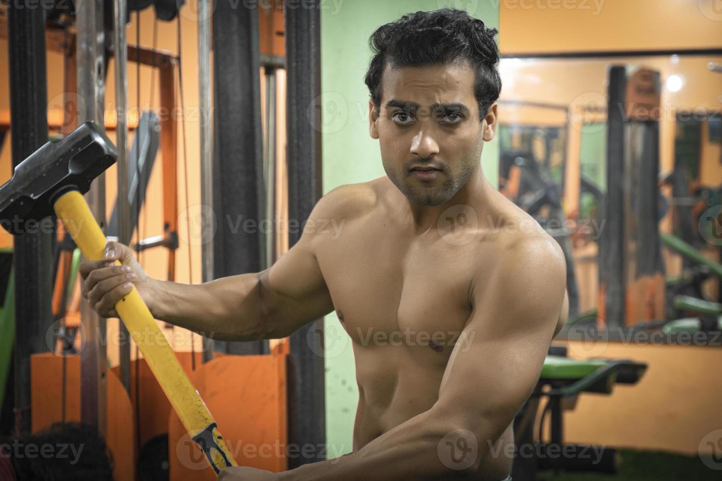 Young man with hammer gym tyre workout healthy man images in gym photo