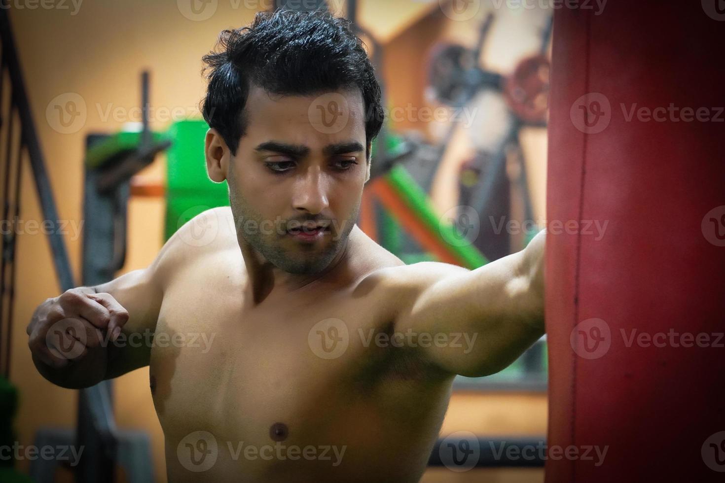 Man punching punch bag in gym photo