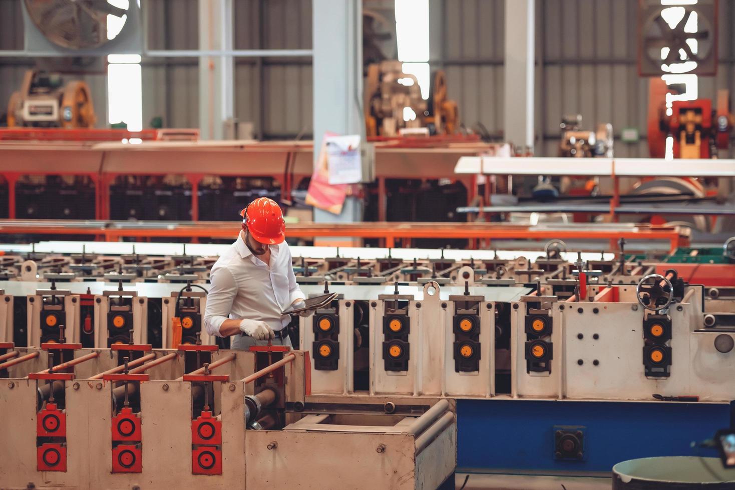 trabajador de fábrica revisando el proceso de la máquina eléctrica en el lugar de trabajo industrial, usando sombrero duro por seguridad foto