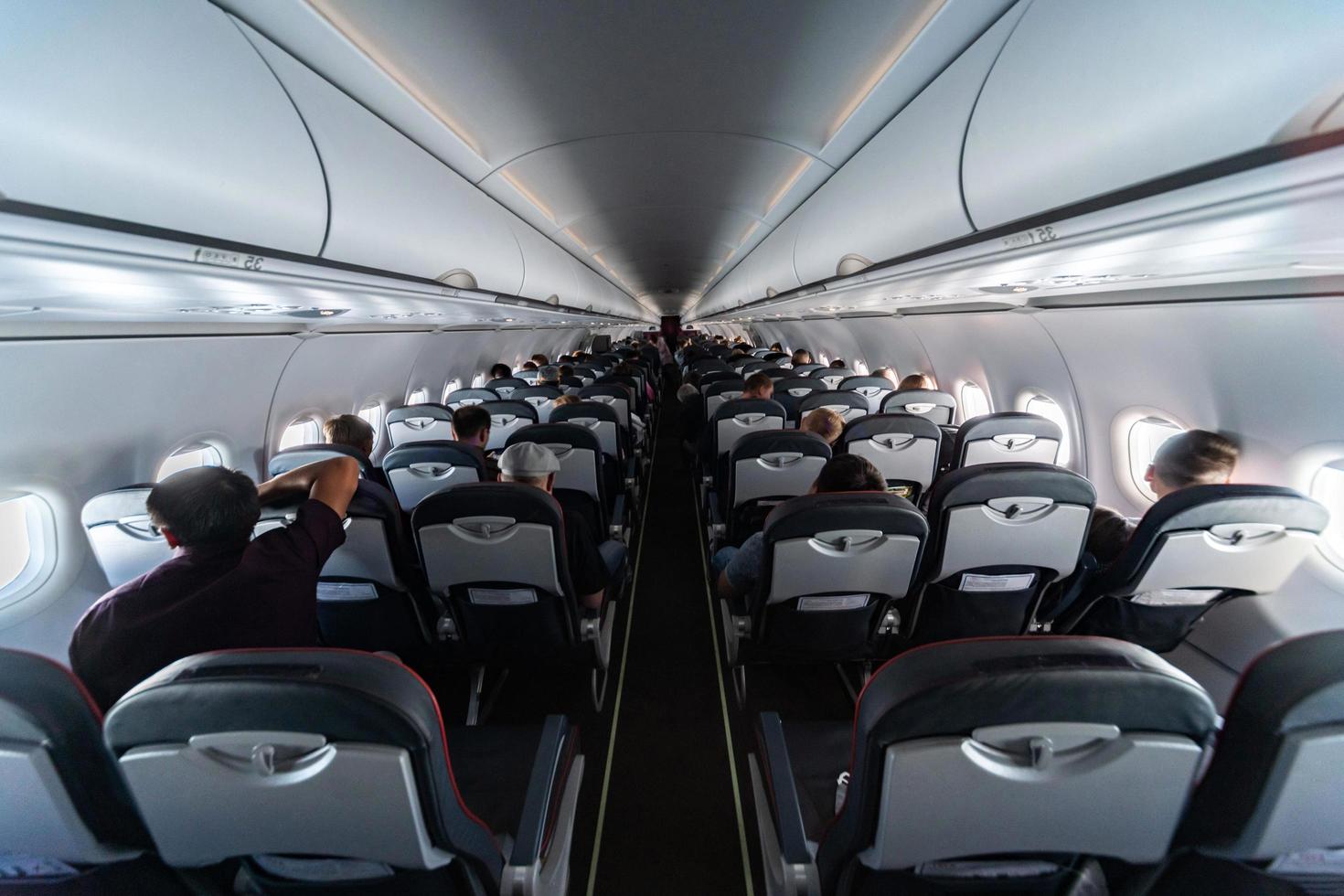 Airplane cabin seats with passengers. Economy class of new cheapest low-cost airlines without delay or cancellation of flight. Travel trip to another country. photo