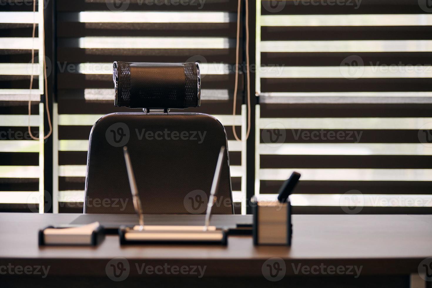 Business office workplace. Work place for chief, boss or other employees. Table and comfortable chair. Light through the half open blinds photo