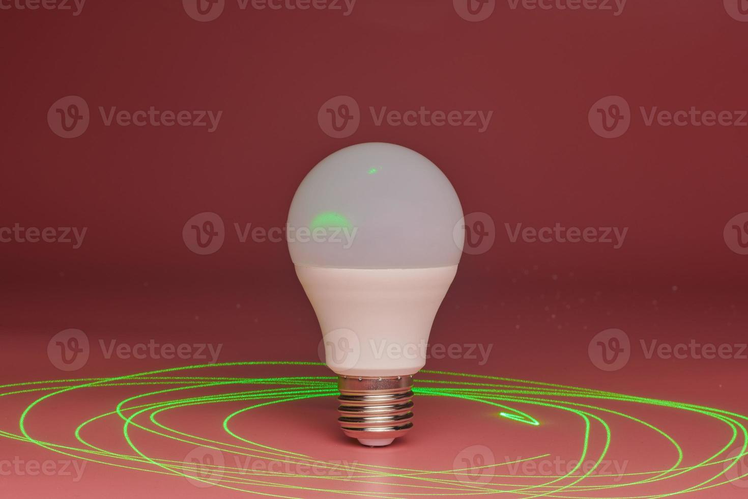 Energy saving light bulb, green laser beam around, copy space. Minimal idea concept. photo