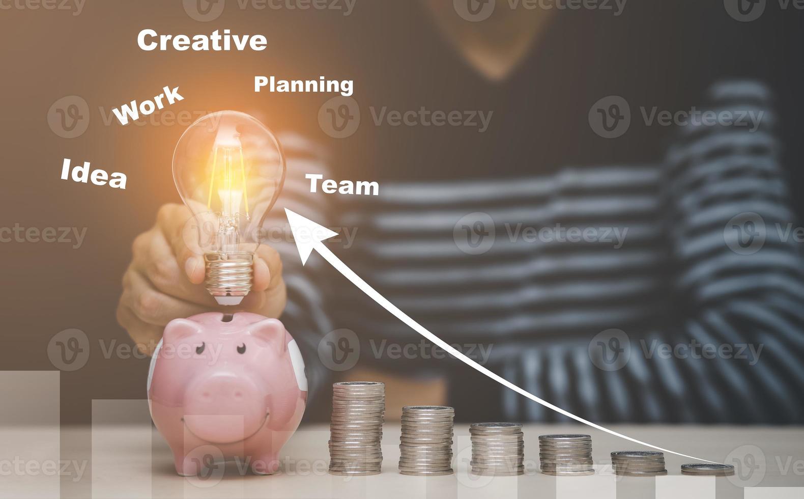 Man hand holding light bulb on coins stack on the wooden table , Saving ideas and investment budget, Creative ideas concept, Stock market or forex trading graph and candlestick chart suitable photo
