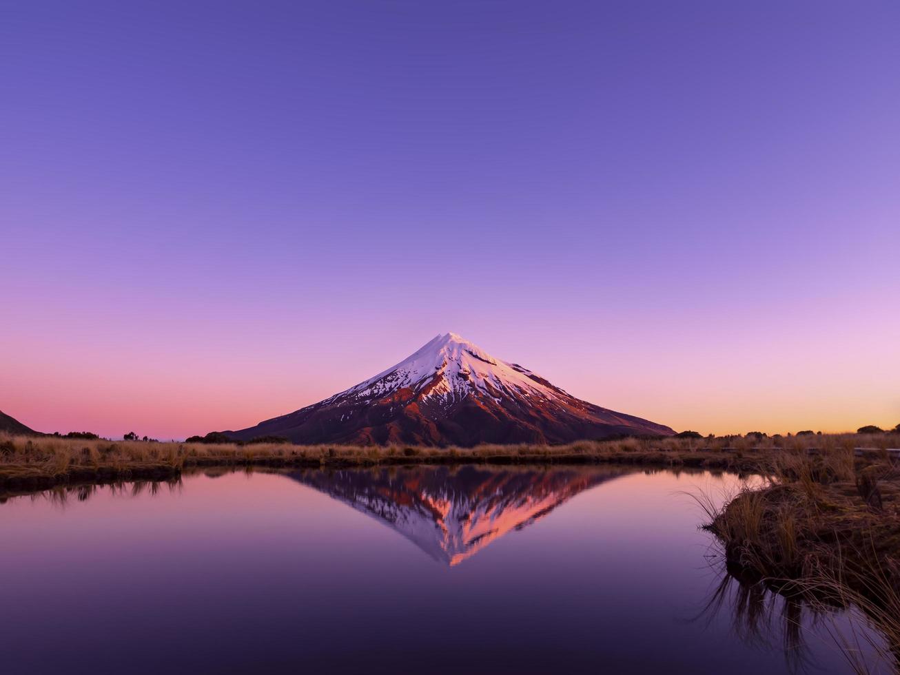 mt taranaki mountain reflejo en el lago tarns nueva zelanda en la noche con hermosos colores de puesta de sol en la nieve foto