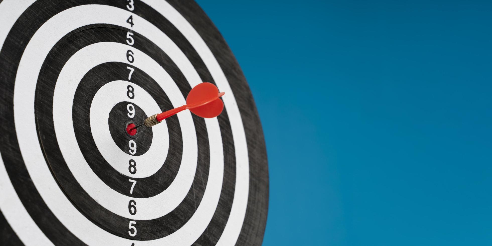 Dartboard on a blue background with arrows hitting the center target photo