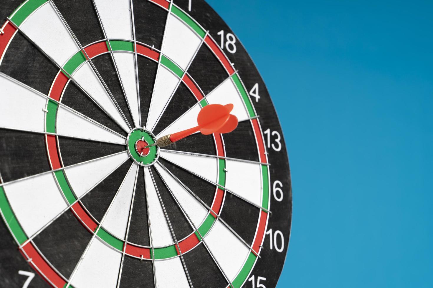 Dartboard on a blue background with arrows hitting the center target photo
