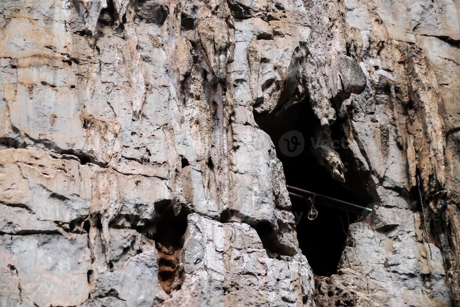 Bat cave entrance on cliff of rock mountain. photo