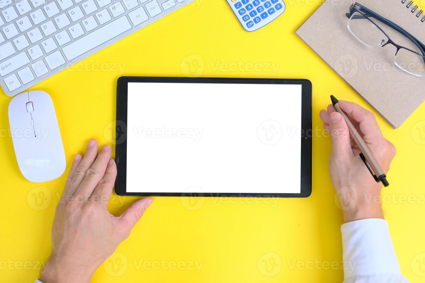 la tableta de pantalla blanca en blanco y los dispositivos asociados rodean una imagen de vista superior de una estación de trabajo blanca. foto