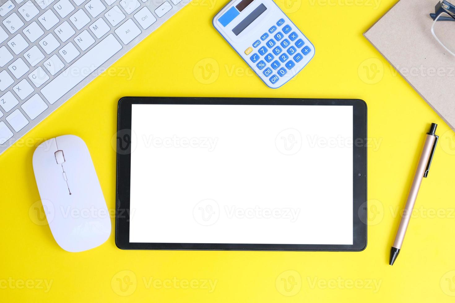la tableta de pantalla blanca en blanco y los dispositivos asociados rodean una imagen de vista superior de una estación de trabajo blanca. foto