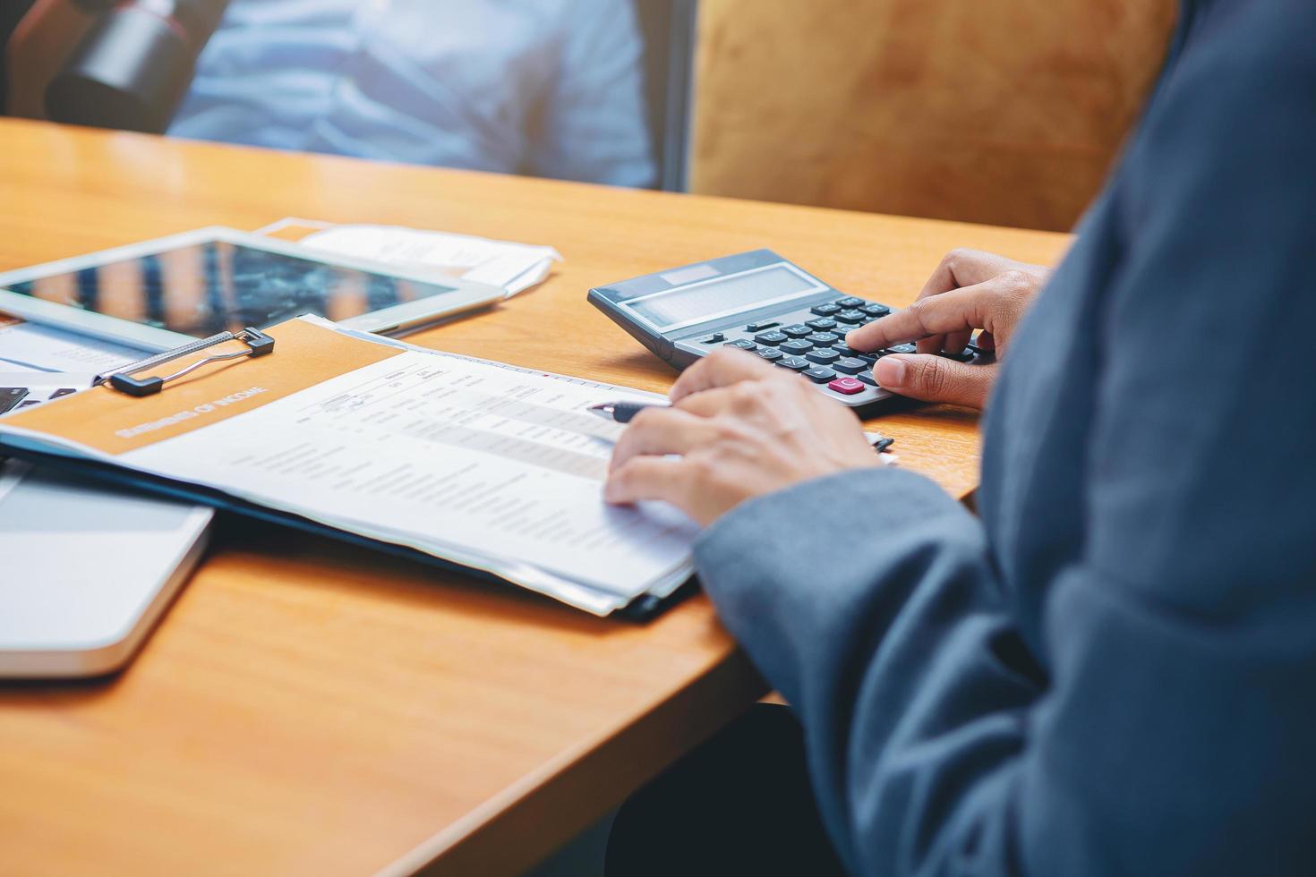 contadora que trabaja en el escritorio usando una calculadora para calcular y verificar el informe financiero. foco seleccionado foto