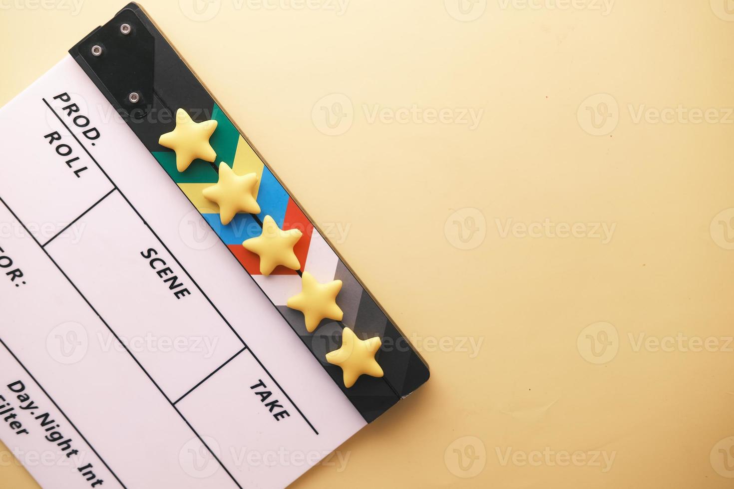 Rating golden stars and movie clapper board on color background photo