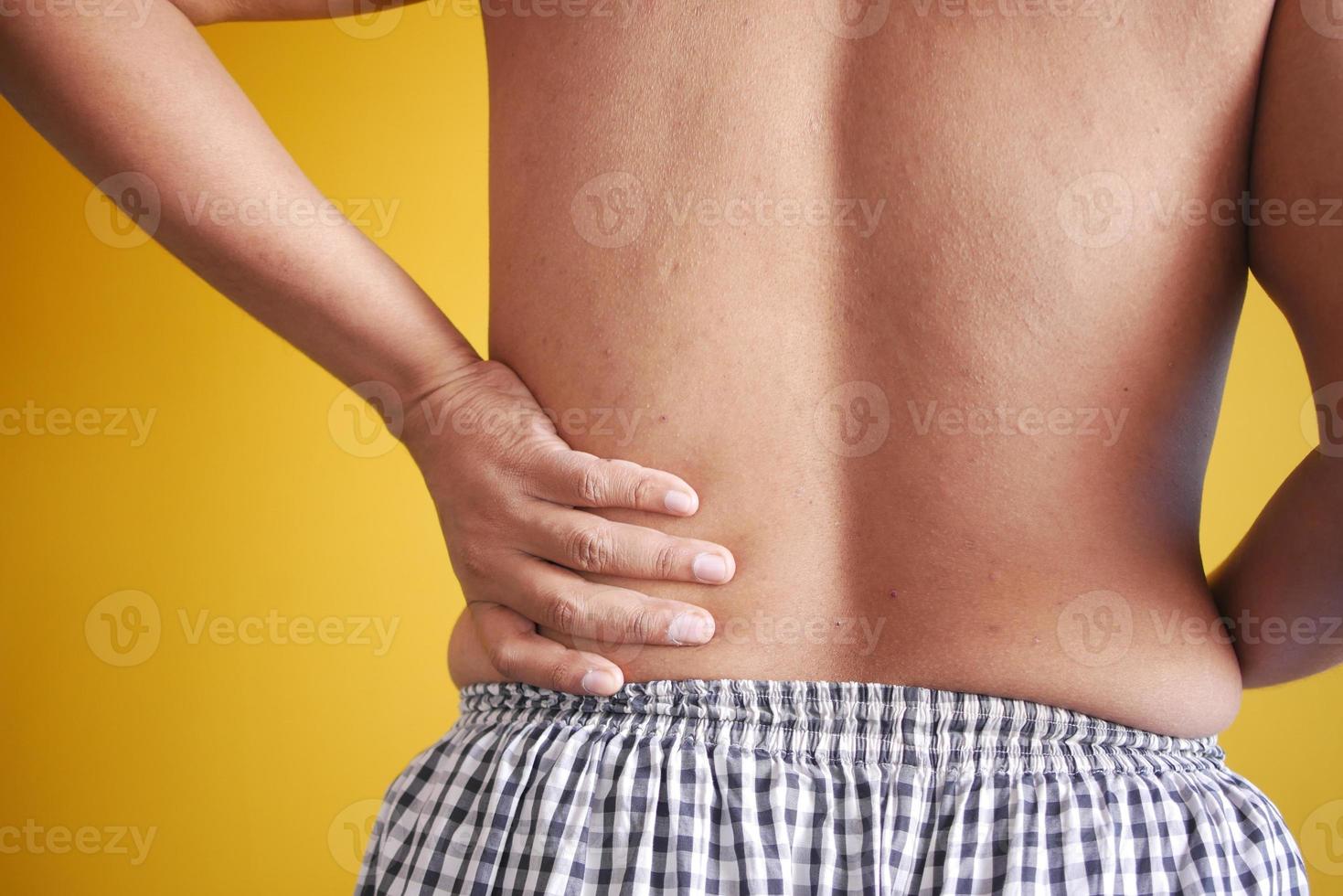 young man suffering back pain close up photo