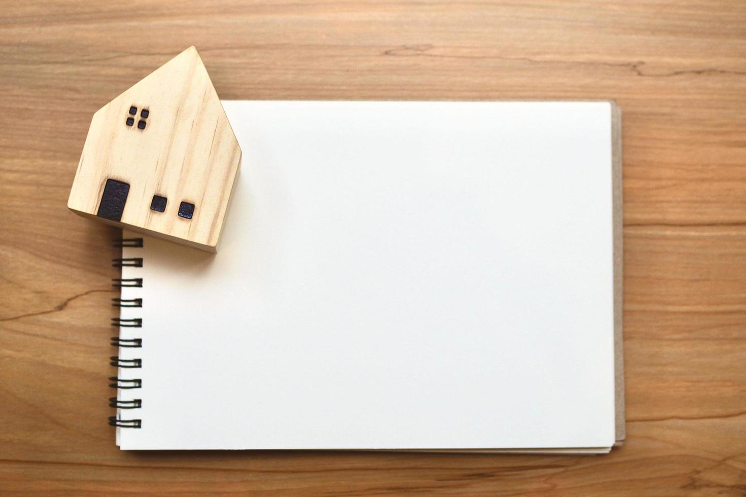 Business creative composition. Top horizontal view of woodden house and notebook on woodden table background. photo