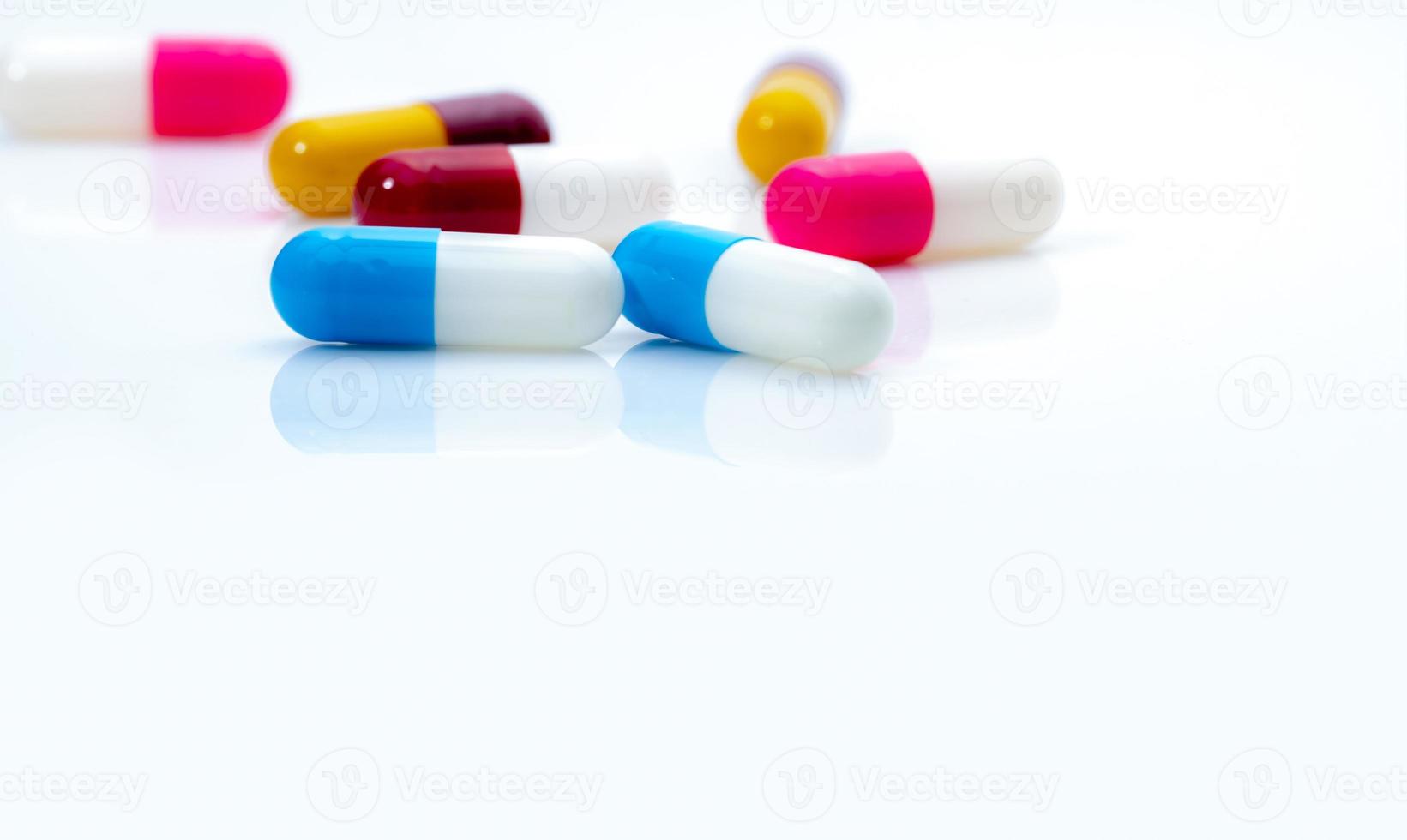 Selective focus on blue-white antibiotic capsule pills on white background. Prescription drugs. Colorful capsule pills. Antibiotic drug resistance concept. Pharmaceutical industry. Superbug problems. photo