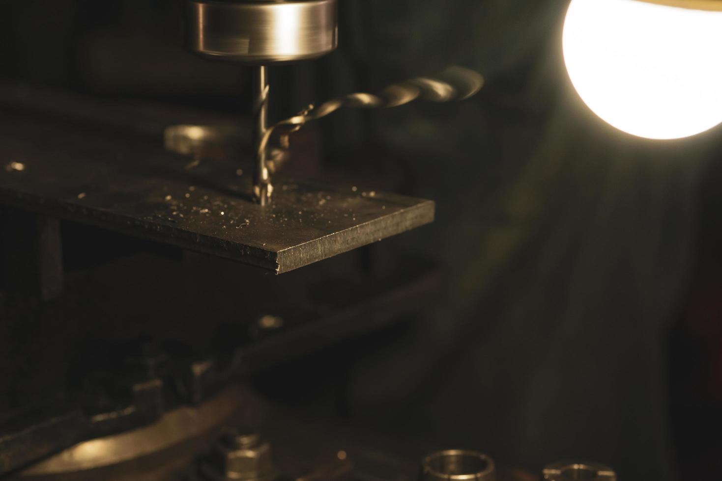 Fresado de placa de metal de enfoque selectivo con fresadora en fábrica. herramienta para fresar y taladrar piezas de metal con bombilla. fábrica de fabricación de acero. proceso de molienda máquina en taller. foto