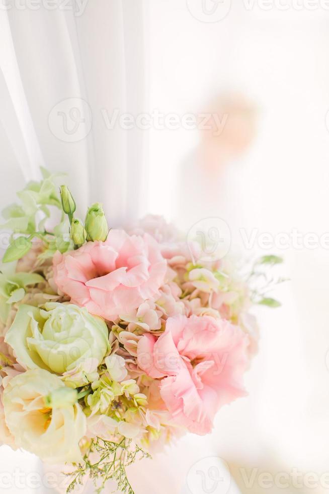 Colorful pink and light green floral arrangement tied to an arch in a wedding ceremony photo