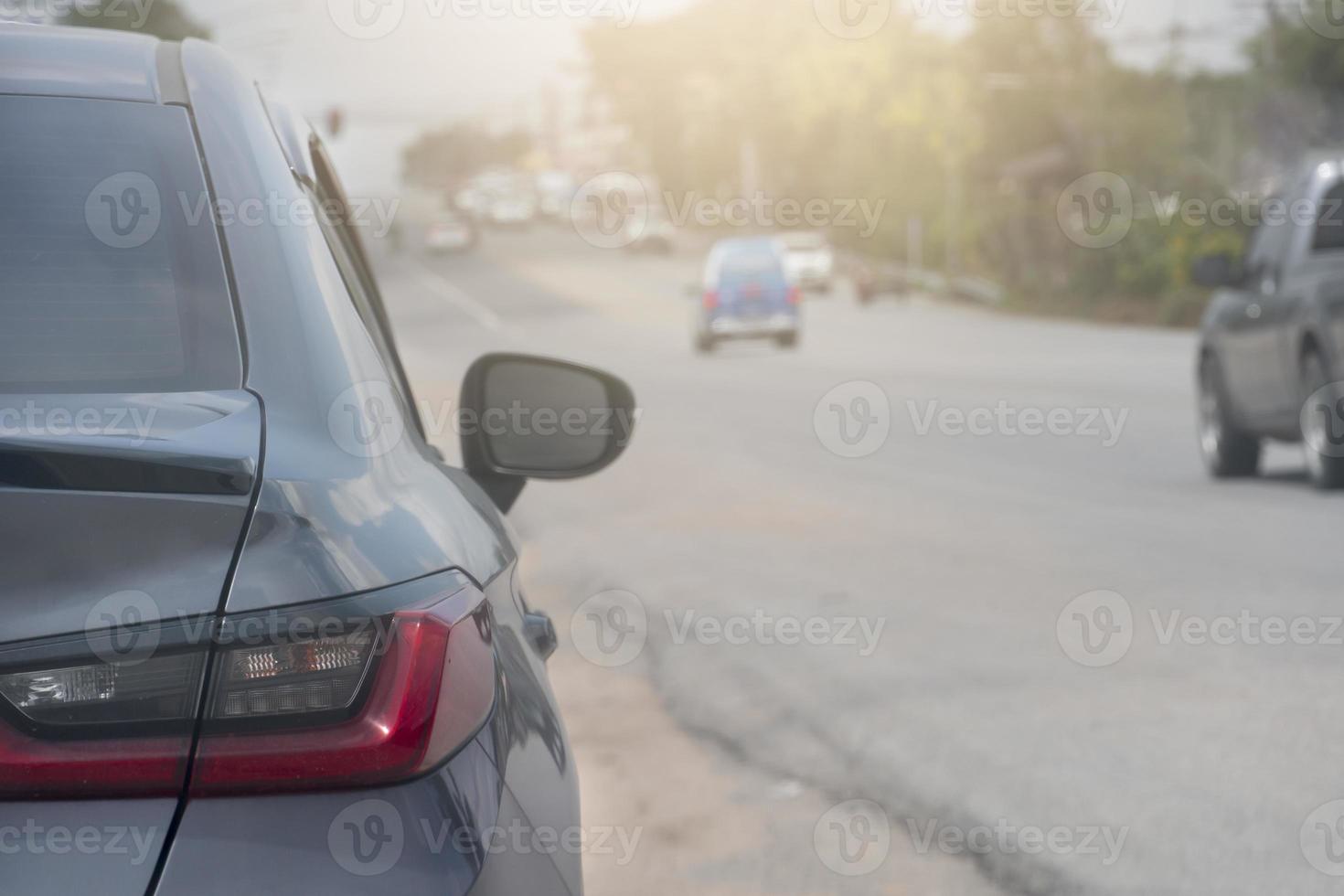 aparcamiento gris al lado de la carretera de tierra. con otros coches circulando por la carretera asfaltada. ambiente en la noche del país. foto