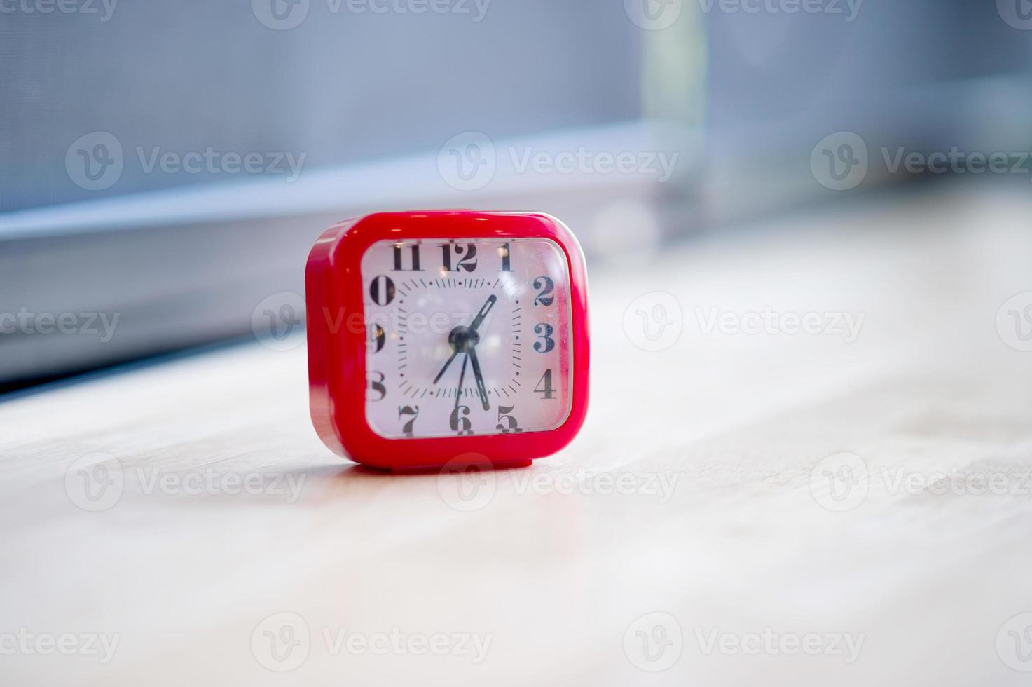 despertador rojo colocado en suelos de madera coloridos, concepto de tiempo foto