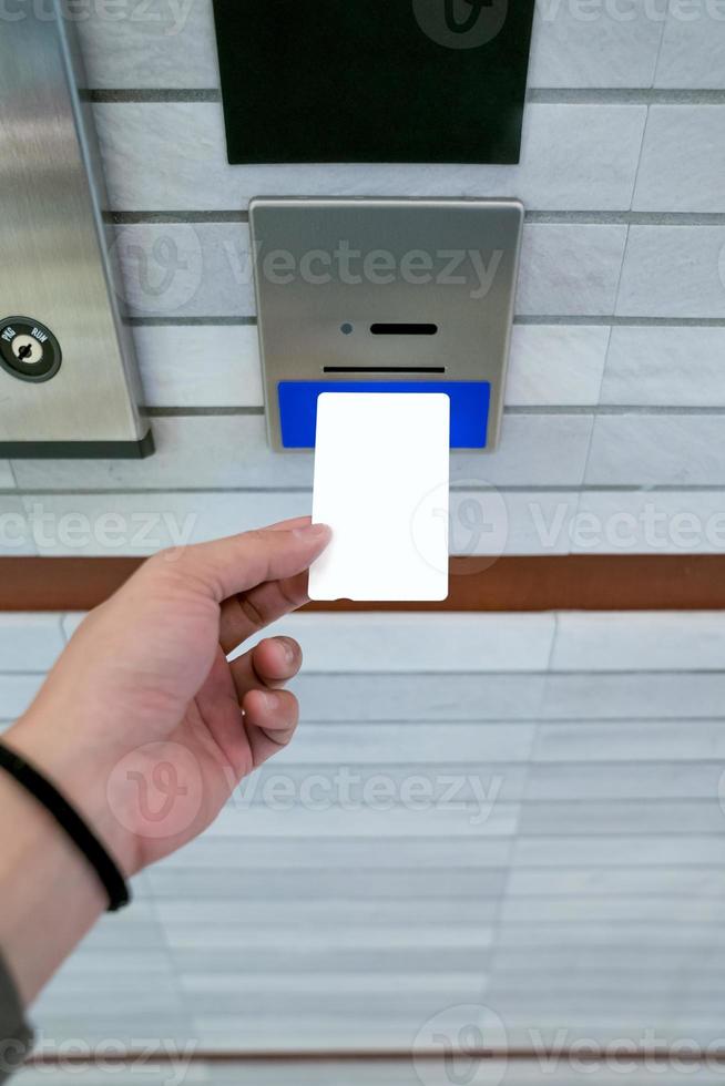 securing lift or elevator access control, man's hand is holding a key card lay up to insert in card hold for unlocking elevator doors before up or down. photo