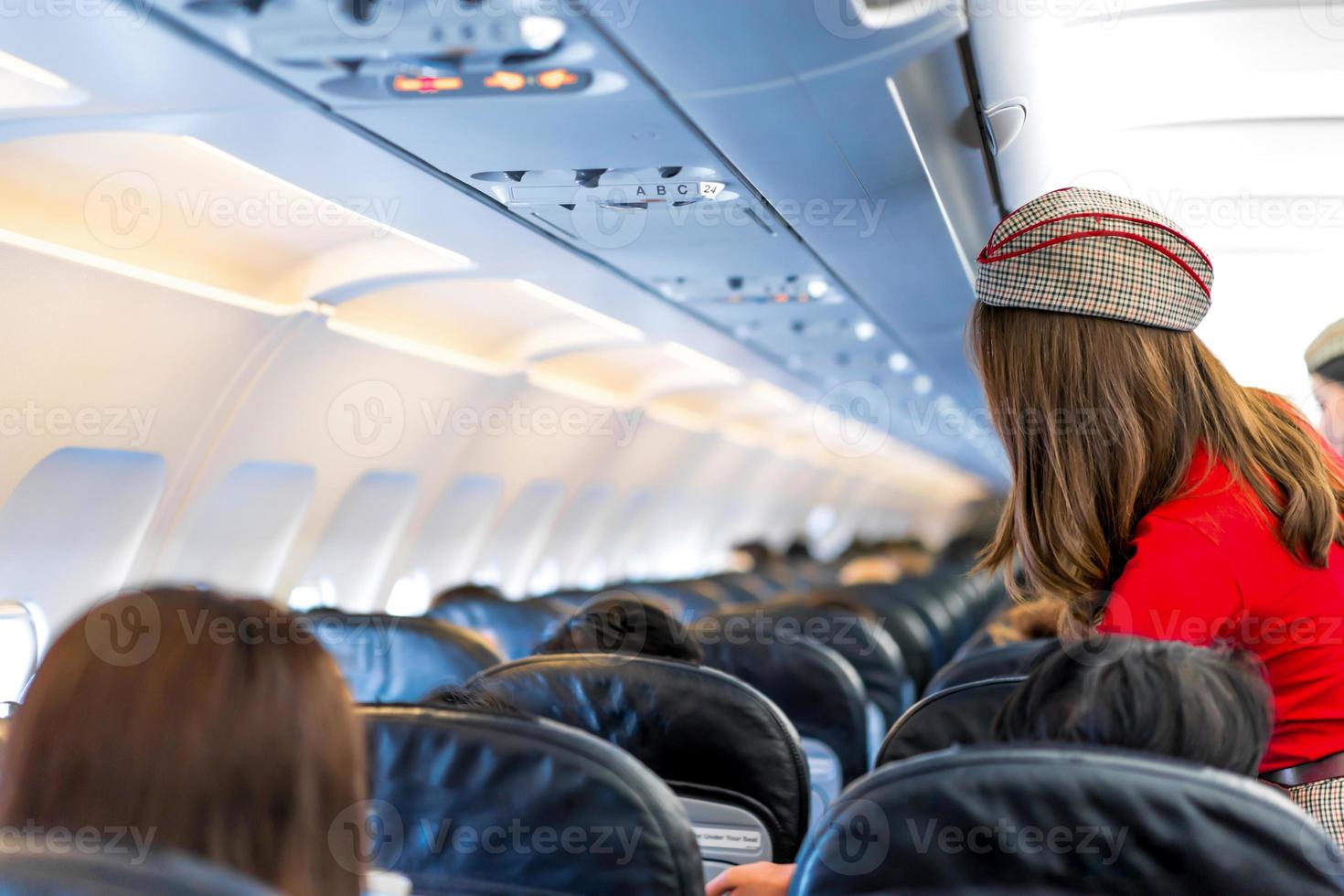 air hostess in red uniform services and checks for all correct at all around the passenger seat photo