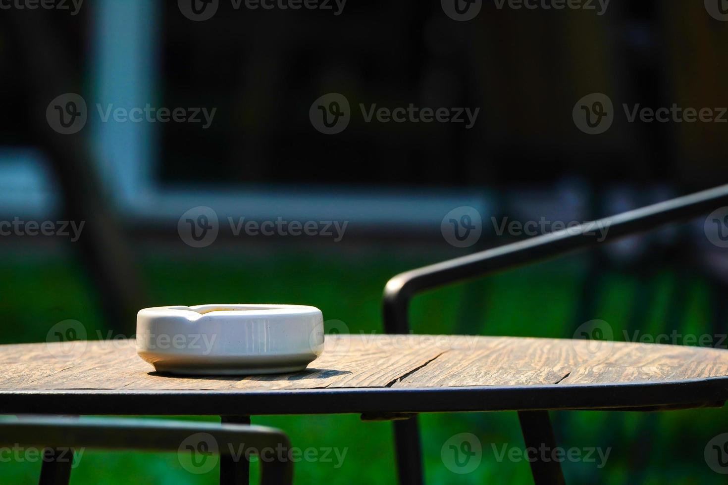 only 1 white ashtray on the dark wood table in the dark environment photo