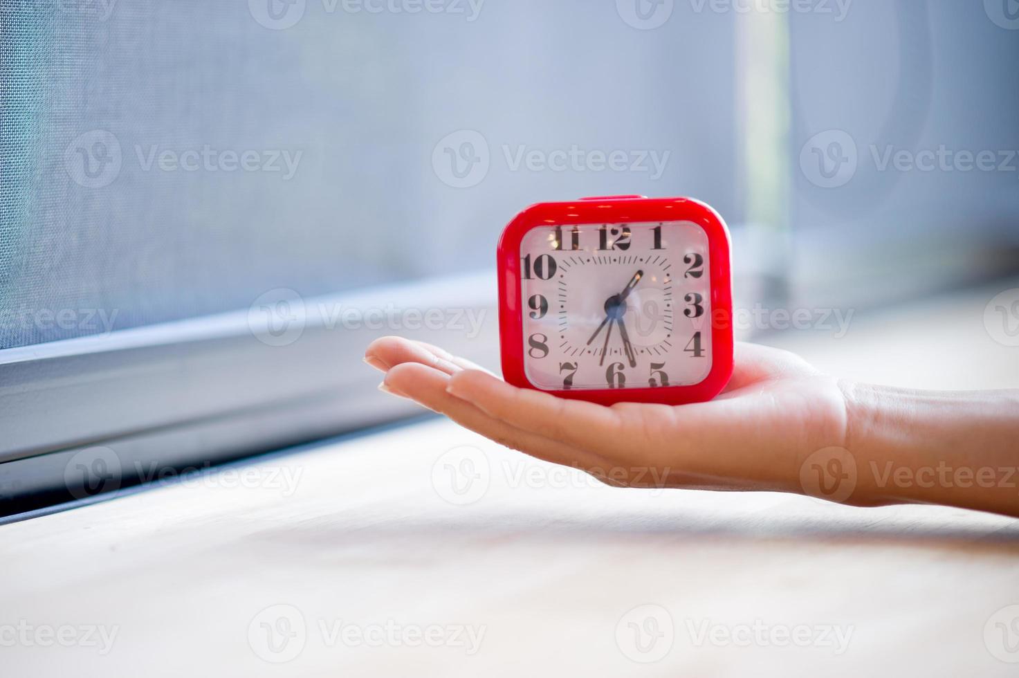 Hand and red alarm clock that shows the alarm at all Every morning, the concept of punctuality photo