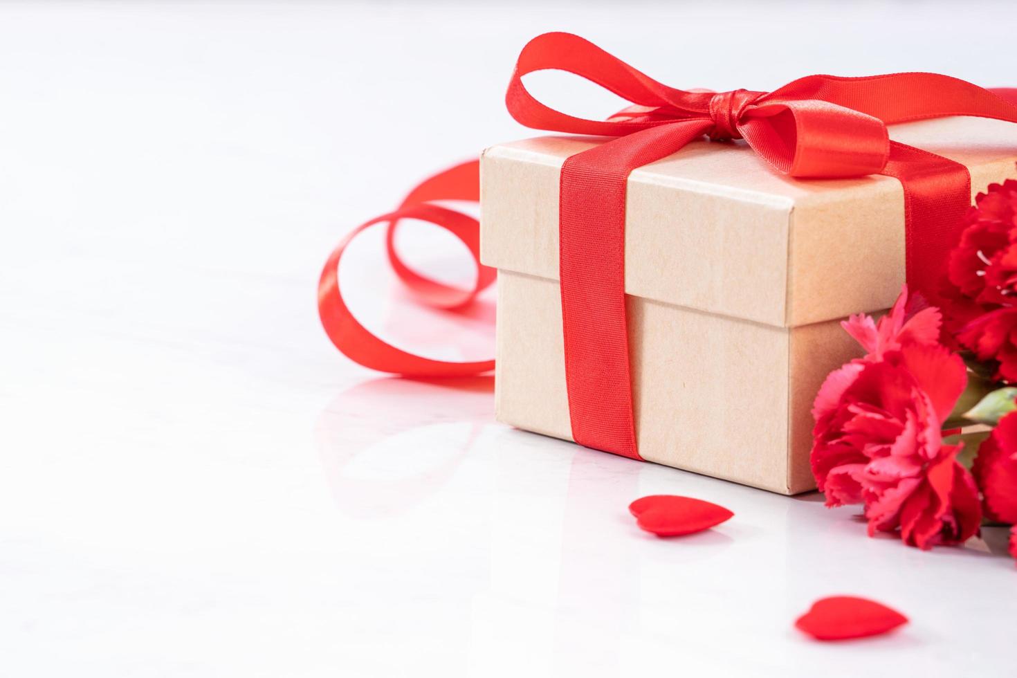 May mothers day handmade giftbox wishes photography - Beautiful blooming carnations with red ribbon bow box isolated on modern marble desk, close up, copy space, mock up photo