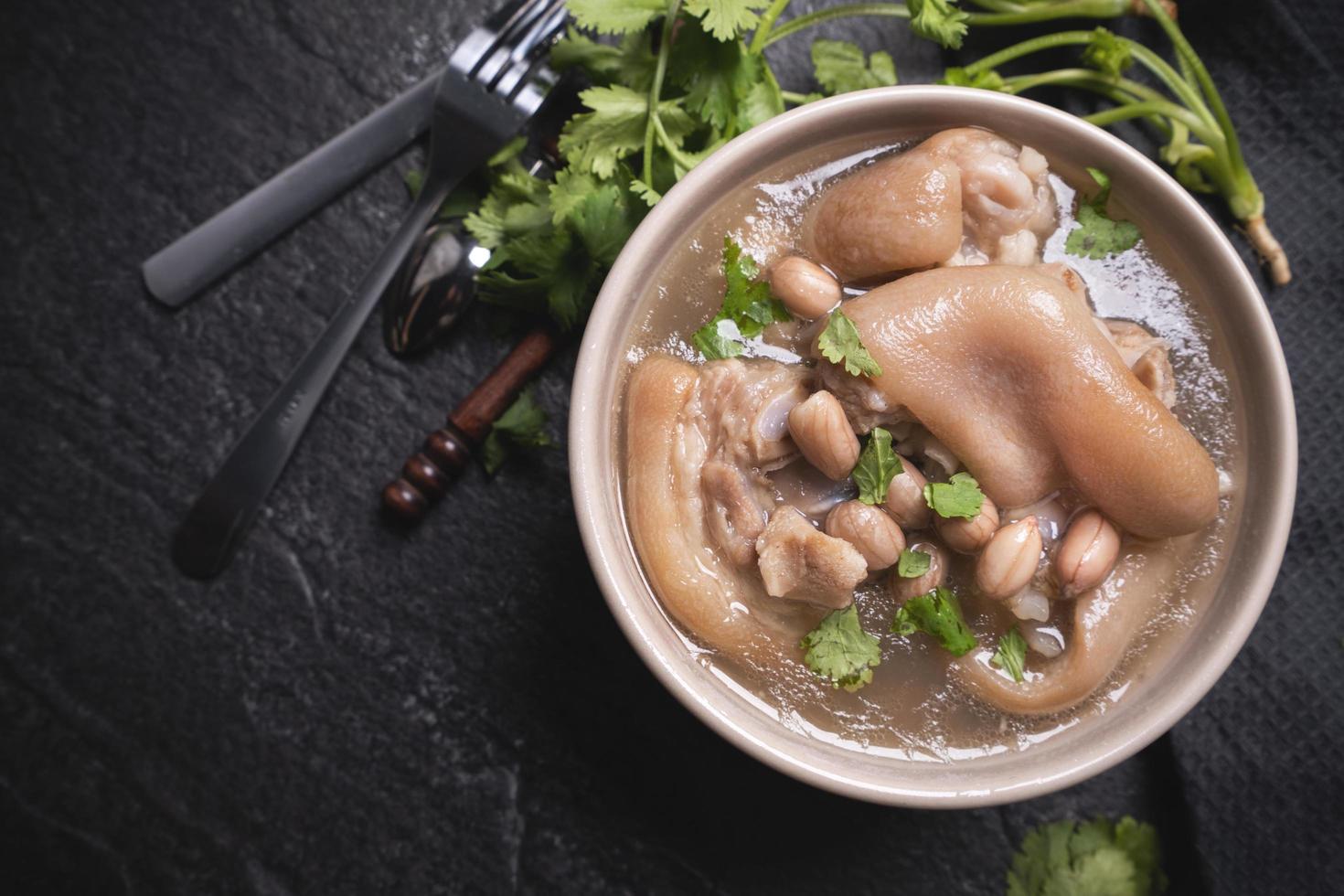 Top view, close up, copy space, Taiwan asian distinctive street food, peanut pork knuckle soup in a beige ivory creamy-white colored bowl isolated on dark shale slate table photo