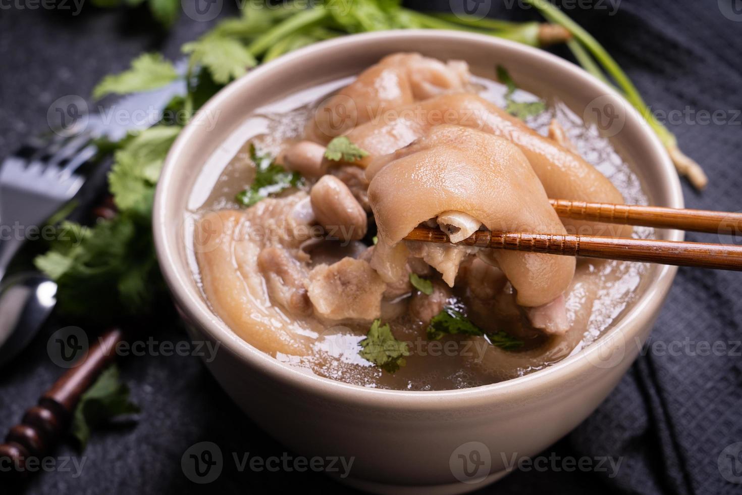 Top view, close up, copy space, Taiwan asian distinctive street food, peanut pork knuckle soup in a beige ivory creamy-white colored bowl isolated on dark shale slate table photo