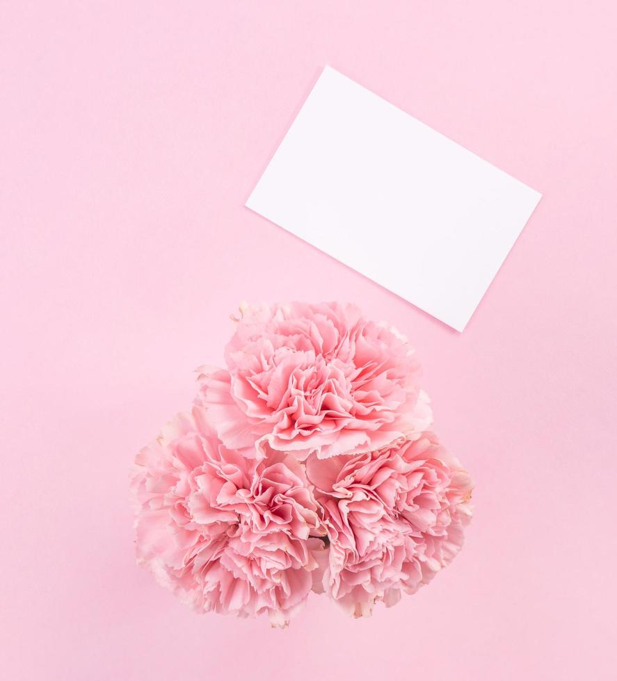 Top view, flat lay, mock up, copy space, handwritten greeting card template isolated with pale pink background, idea concept of thanks, wishes, craft carnations bouquet photo