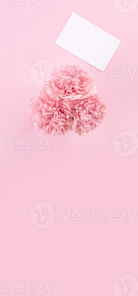 Top view, flat lay, mock up, copy space, handwritten greeting card template isolated with pale pink background, idea concept of thanks, wishes, craft carnations bouquet photo