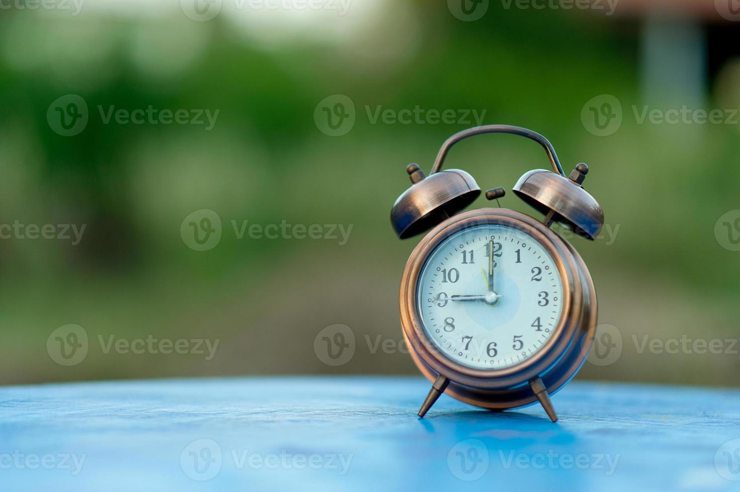 imagen de reloj de alarma dorada colocada en una mesa azul, concepto puntual de fondo verde con espacio de copia foto