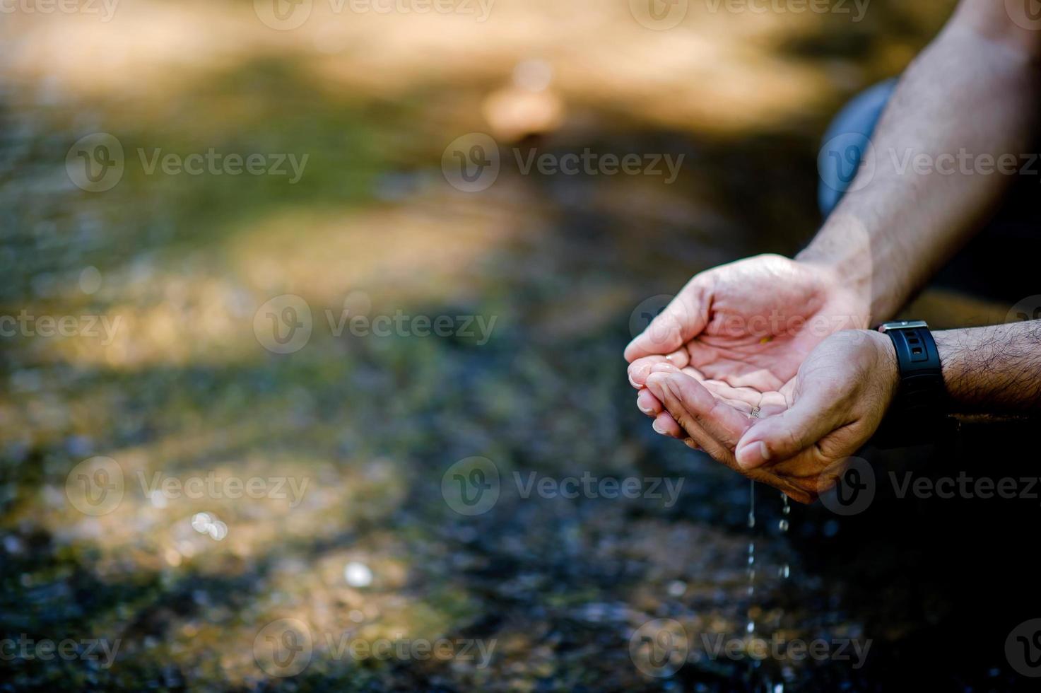 Hands and water flowing from natural waterfalls Water concept from natural waterfall photo