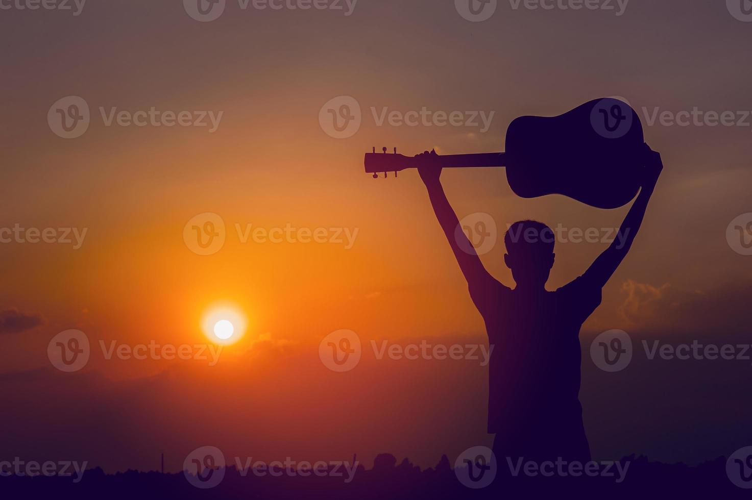 The silhouette of a guitarist who holds a guitar and has a sunset, silhouette concept. photo