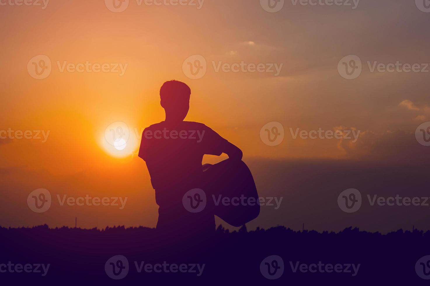 The silhouette of a guitarist who holds a guitar and has a sunset, silhouette concept. photo