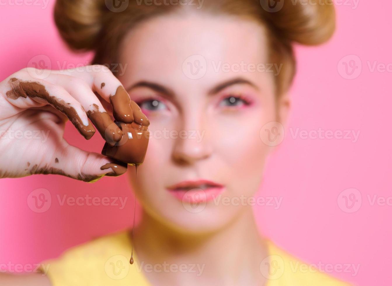retrato de una linda y atractiva mujer joven rubia con dulces de chocolate en los dedos foto