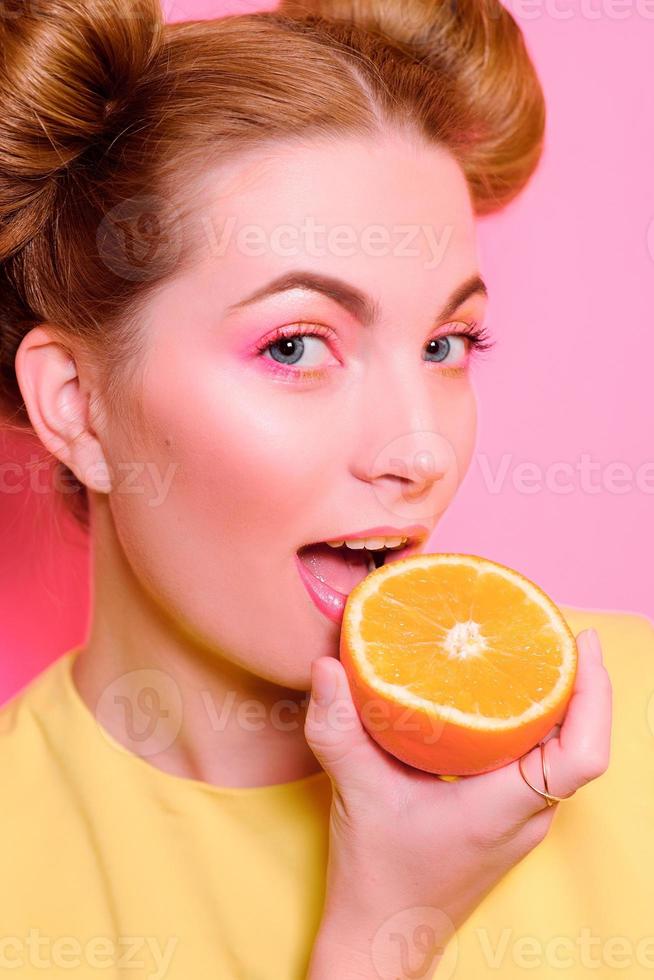 Portrait of stylish cute young blonde woman with oranges on pink background photo