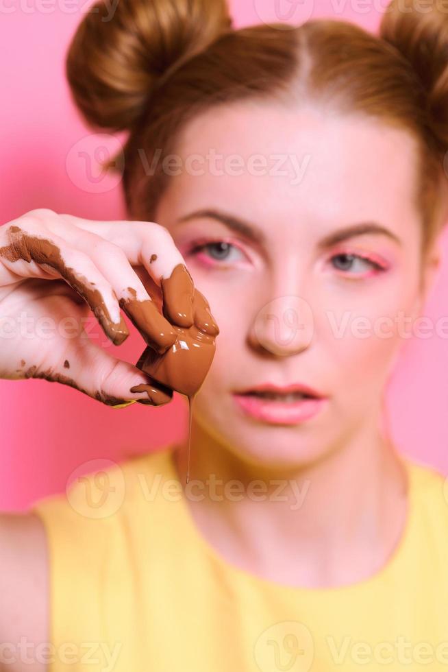 retrato de una linda y atractiva mujer joven rubia con dulces de chocolate en los dedos foto