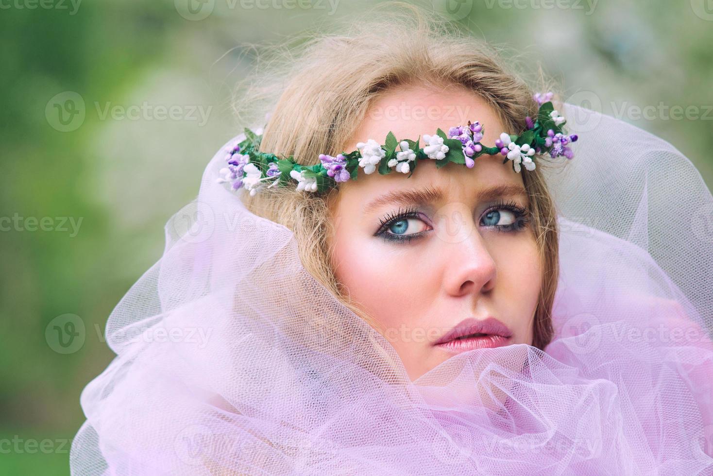 beautiful young blonde woman in flower wreath blooming trees in spring photo
