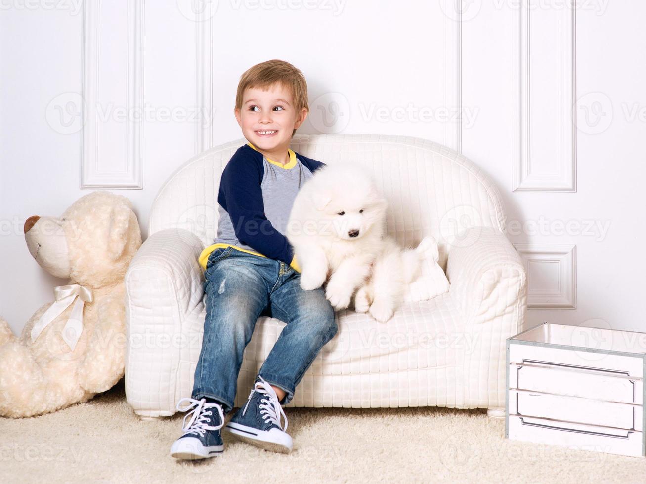 smiling little boy three years old playing with white puppies of Samoyed in studio photo