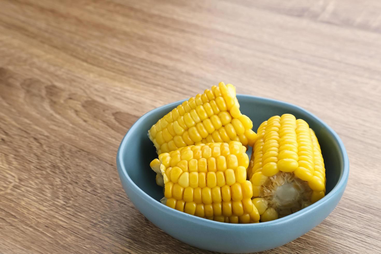 Jagung manis rebus or boiled sweet corn slices served on bowl on wooden background. Space for text. photo